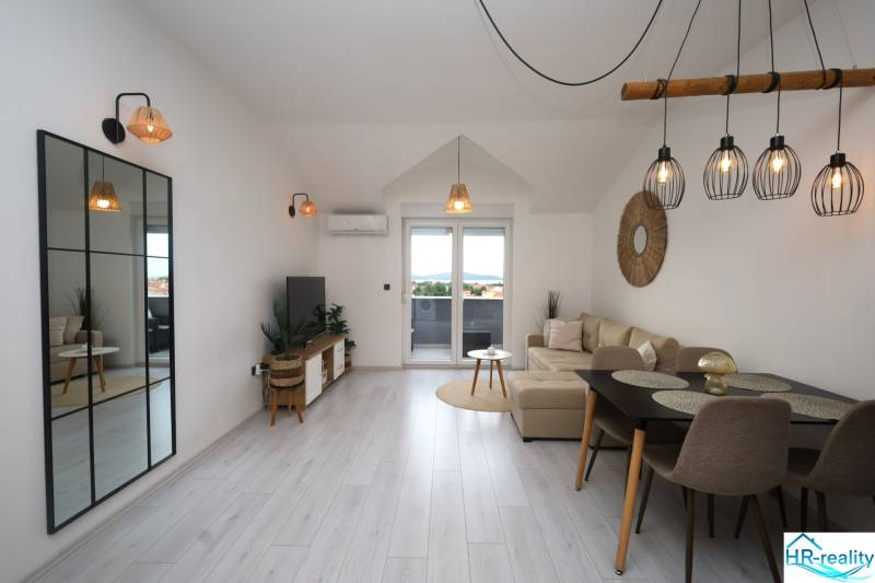 Wohnzimmer in einer Ferienwohnung mit Holzboden und großem Spiegel.