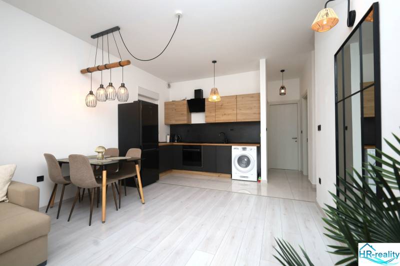 Küche in einer Ferienwohnung mit Esstisch und Boden in Holzoptik.