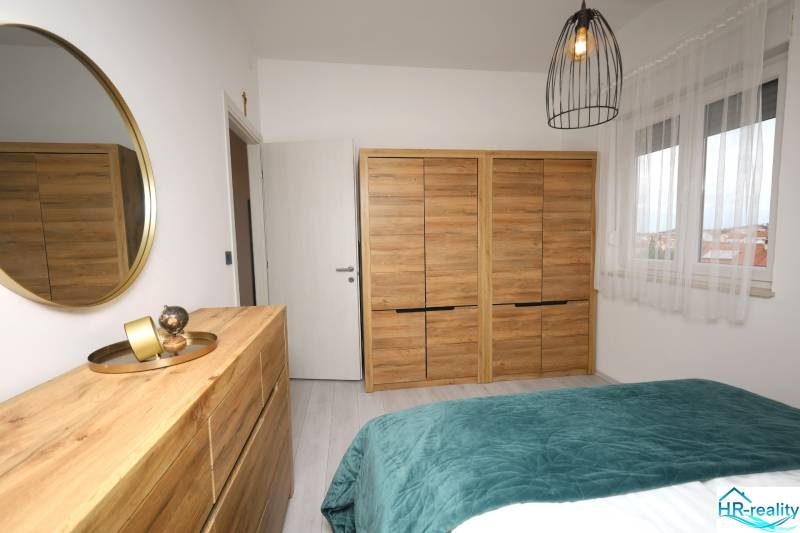 Schlafzimmer im Ferienapartment mit Holzdekor, Spiegel und Dekorationen.