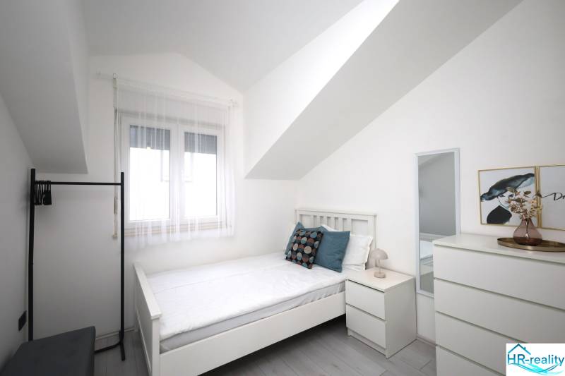 Helles Zimmer mit Bett, Spiegel und Dekorationen in einer Ferienwohnung.