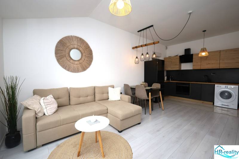 Wohnzimmer in einer Ferienwohnung mit Küche, Sofa und dekorativen Elementen an der Wand.