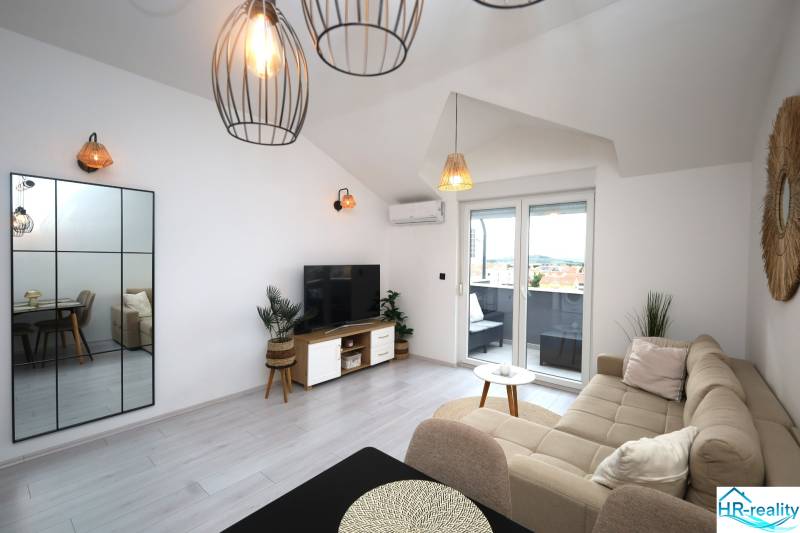 Wohnzimmer im Ferienapartment mit bequemer Couch, TV und Balkon.