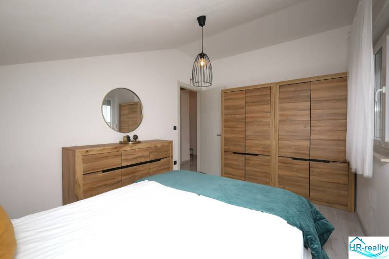 Für eine Ferienwohnung sind typische Schränke und eine Kommode mit Holzdekor und Spiegel.