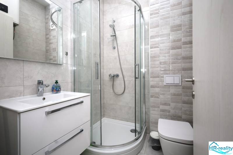 Badezimmer in einer Ferienwohnung mit moderner Duschkabine und minimalistischer Einrichtung.