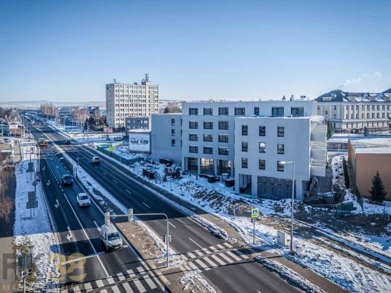Ein Gebäude in Poprad an einer stark befahrenen Straße, verschneite Landschaft, blauer Himmel.