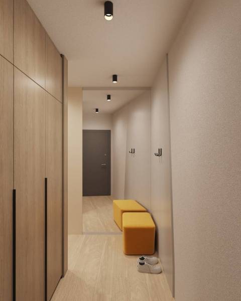 Innenraum eines Gebäudes mit Holzboden, Kleiderschrank, Spiegel und gelber Sitzgelegenheit.