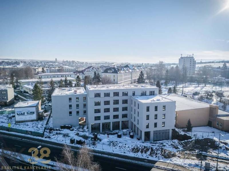 Ein Gebäude in der Stadt Poprad, umgeben von einer verschneiten Landschaft und weiteren Bauwerken.