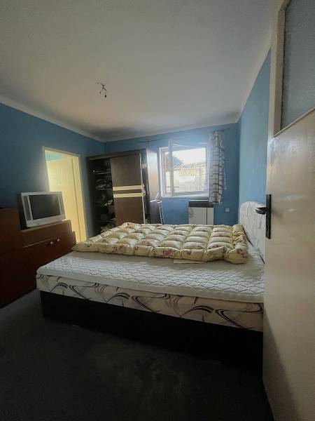 Ein Schlafzimmer mit einem Bett, einem dunklen Kleiderschrank, einem Fernseher und blauen Wänden in einem Einfamilienhaus.