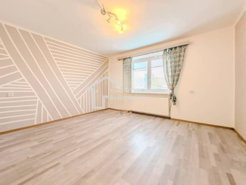 Ein Zimmer in einem Einfamilienhaus mit geometrischer Malerei und einem Boden in Holzoptik.