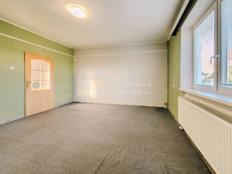 Innenraum eines Einfamilienhauses mit bunten Wänden, Teppichboden und einem Fenster mit Jalousien.