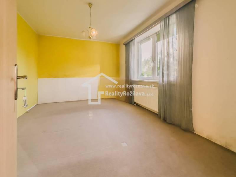 Ein Zimmer in einem Einfamilienhaus mit einem großen Fenster, gelbe Wände und Vorhänge.