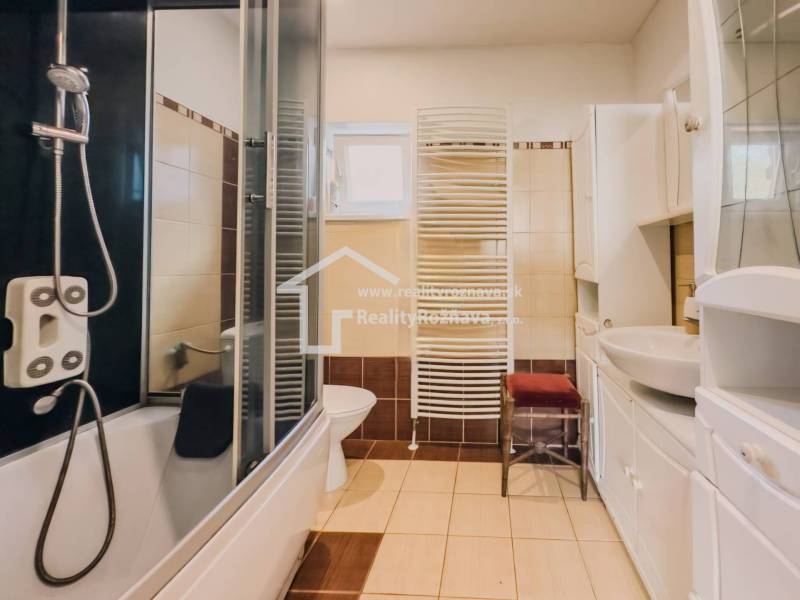 Badezimmer in einem Einfamilienhaus mit Badewanne, Dusche, Waschbecken und Heizkörper.