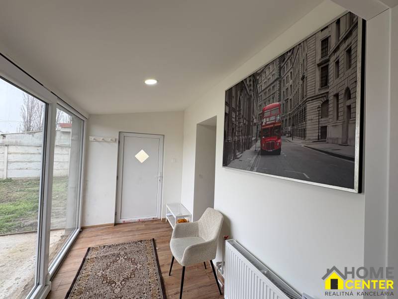 Innenraum einer Einzimmerwohnung mit Holzboden, Glastüren und Kunst an der Wand.