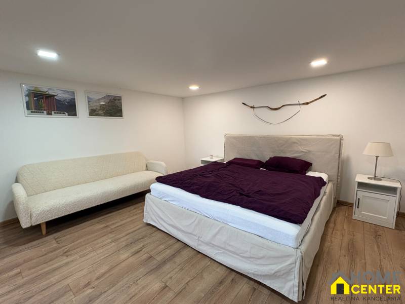 Schlafzimmer in einer Einzimmerwohnung mit Sofa, Bett und Holzboden.