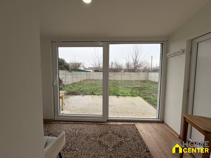 Einzimmerwohnung mit Blick auf den Garten und einem Boden in Holzoptik.