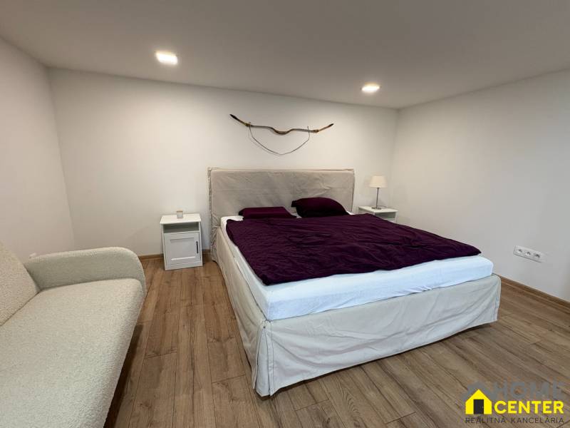 Schlafzimmer in einer Einzimmerwohnung mit Holzboden, Bett und dekorativem Element an der Wand.