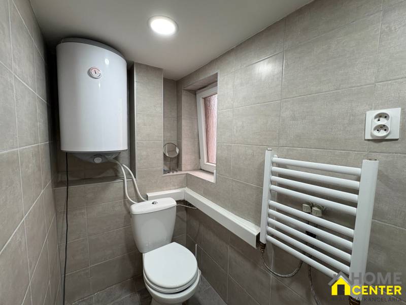 Badezimmer in einer Einzimmerwohnung mit Sanitäreinrichtungen, Boiler und weißem Handtuchheizkörper.