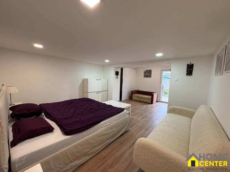 Ein Schlafzimmer in einer Einzimmerwohnung mit Holzboden, einfache Möbel und Dekorationen.