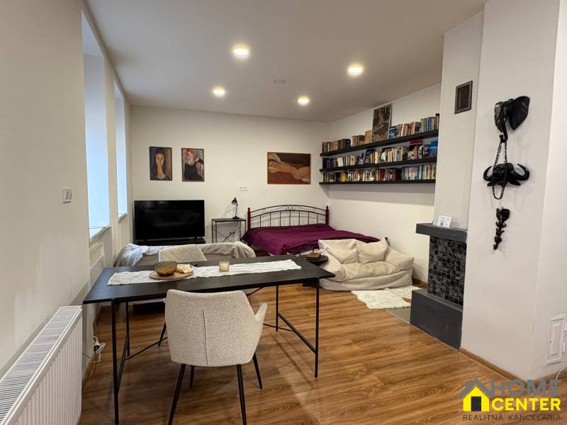 Innenraum einer Einzimmerwohnung mit Holzboden, Bett und Esstisch.