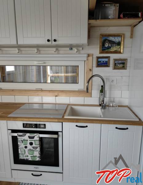 Küchenzeile im Einfamilienhaus mit weißen Schränken, Spüle und eingebautem Backofen.