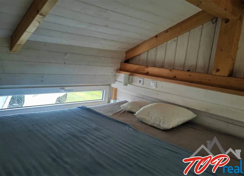 Dachbodenschlafzimmer mit Holzbalken und kleinem Fenster in einem Einfamilienhaus.