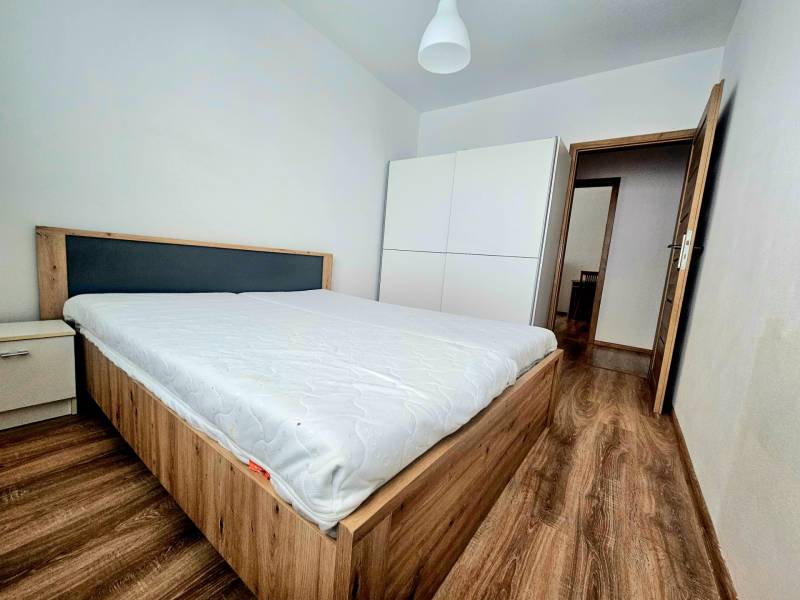 Schlafzimmer in einer 2-Zimmer-Wohnung mit Holzboden, Bett und weißem Schrank.