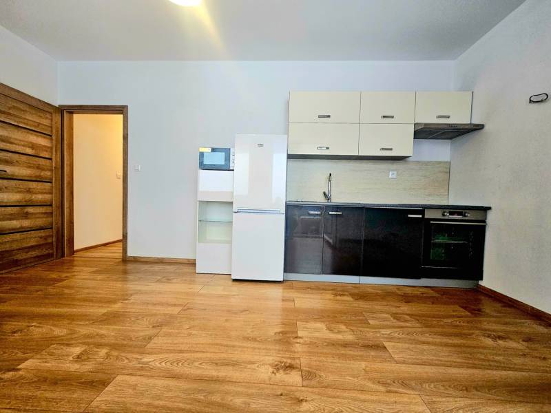 Küche mit Küchenzeile und Geräten in einer 2-Zimmer-Wohnung mit Holzboden.