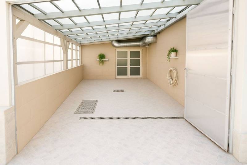 Überdachte Terrasse mit Pflanzen, Türen und Kanalisation im Gebäude.