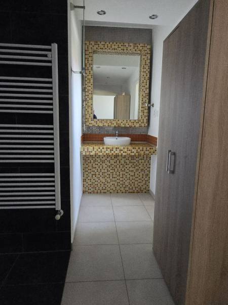 Badezimmer mit Waschbecken, Mosaik und Handtuchhalter, Boden mit Holzdekor.