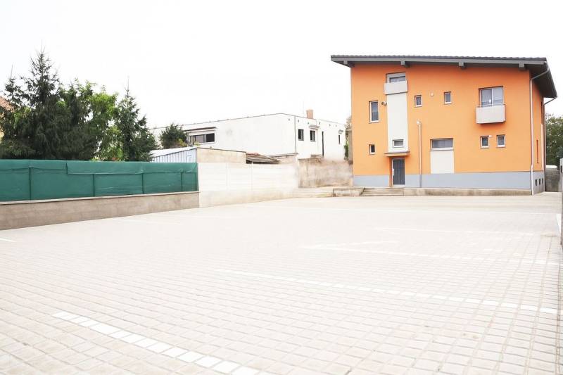Oranges Gebäude in Šaľa mit steilem Dach und befestigtem Parkplatz.