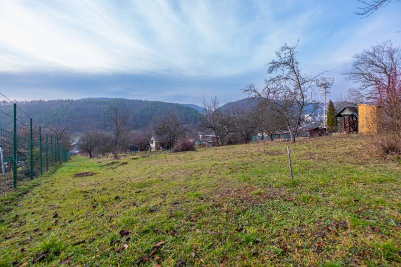 Ein Garten mit Blick auf die Hügel und eine Hütte in Prešov, umgeben von Bäumen und einem Zaun.