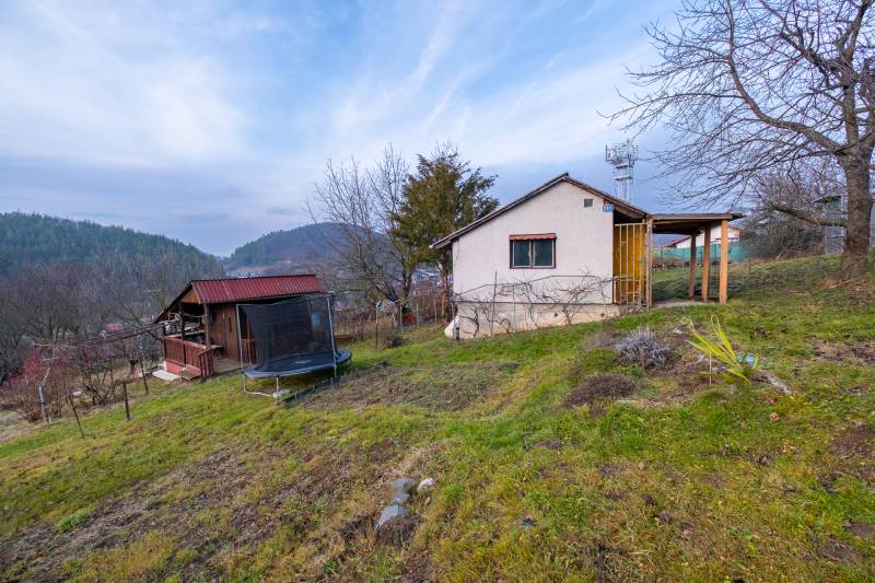 Eine Hütte in Prešov, umgeben von Bäumen, mit Blick auf die Hügel und einem Trampolin im Garten.