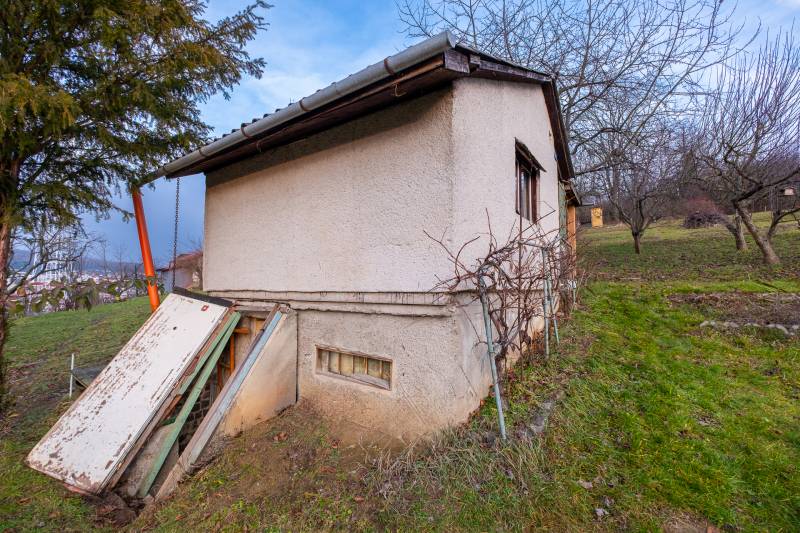 Eine Hütte in Prešov, umgeben von Grün, mit einfachem Putz und einem Außeneingang.