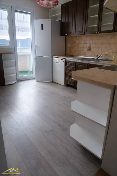 Küche in einer 3-Zimmer-Wohnung mit Holzboden, weißem Kühlschrank und Geschirrspüler.