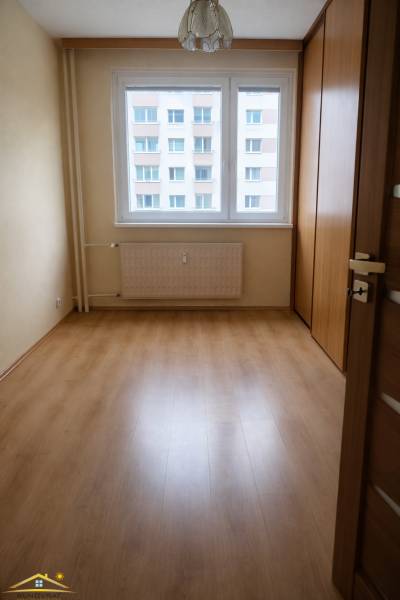 Ein Zimmer mit einem Holzboden und einem großen Fenster in einer 3-Zimmer-Wohnung.