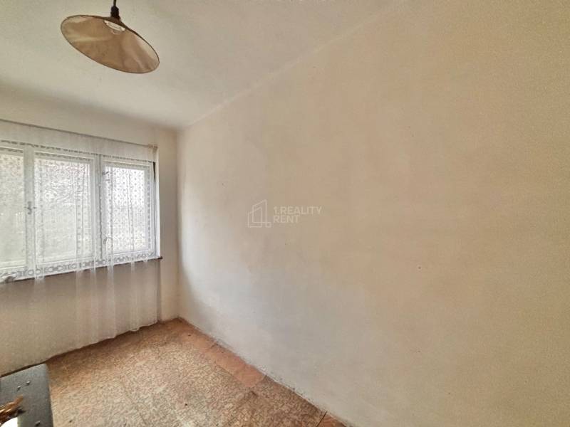 Ein Zimmer in einem Einfamilienhaus mit einem Fenster und einem Vorhang, mit Teppichboden.