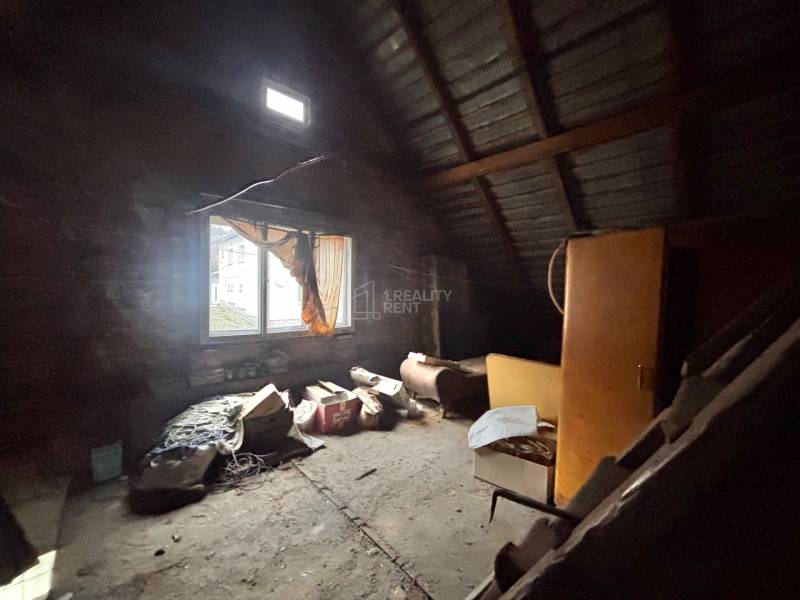 Ein Dachbodenraum mit einem Fenster in einem Einfamilienhaus, voll mit alten Gegenständen und Möbeln.