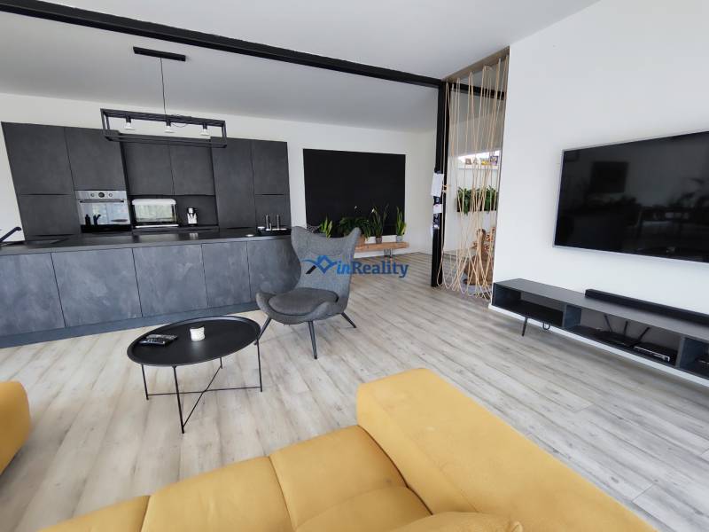 Wohnzimmer mit Küche in einem Einfamilienhaus, Holzboden und gelbes Sofa.