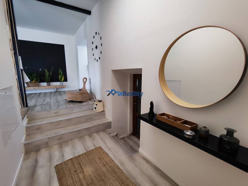 Innenraum eines Einfamilienhauses mit Holzboden, rundem Spiegel und Zimmerpflanzen.