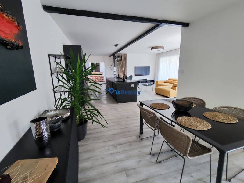 Esszimmer und Wohnzimmer mit Sofa, Tisch und Boden in Holzoptik im Einfamilienhaus.