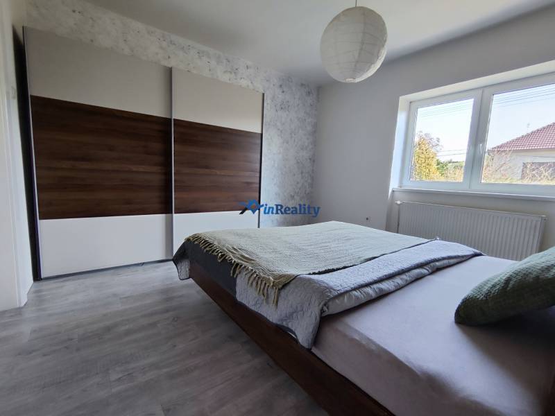 Ein Schlafzimmer in einem Einfamilienhaus mit einem großen Schrank, einem Bett und einem Boden mit Holzdekor.