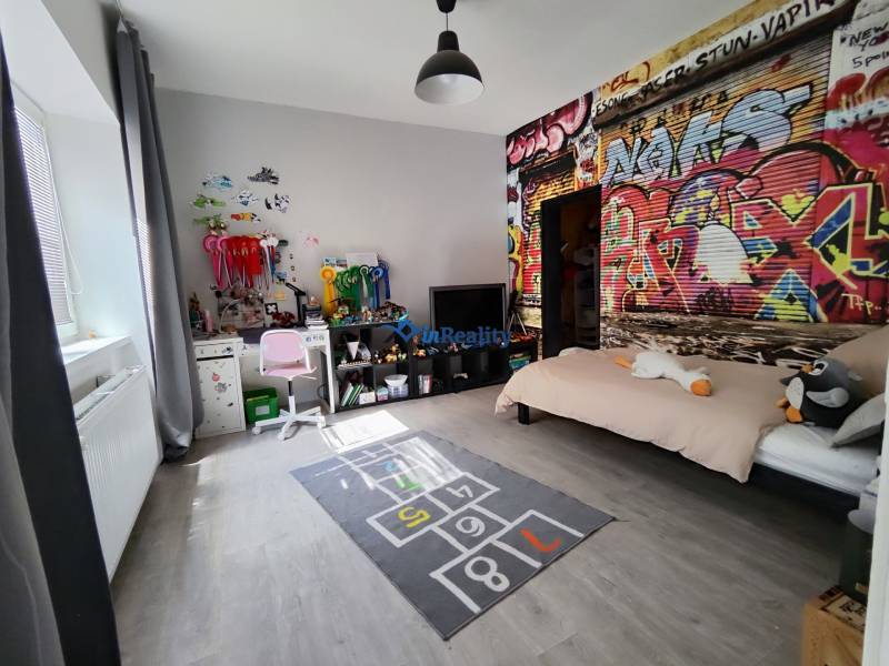 Kinderzimmer im Einfamilienhaus mit Graffiti an der Wand und einem Boden in Holzoptik.