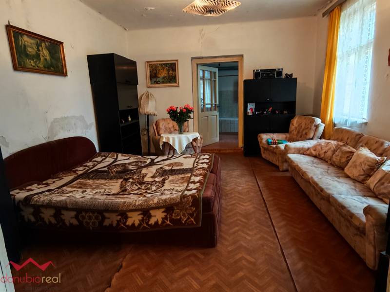 Wohnzimmer in einem Einfamilienhaus mit Blumen, Sofa und Holzboden.