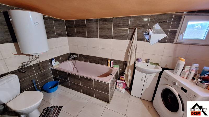 Badezimmer in einem Einfamilienhaus mit Badewanne, Waschmaschine und elektrischem Boiler.