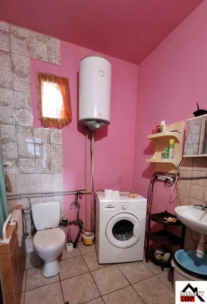 Ein Badezimmer in einem Einfamilienhaus mit Waschmaschine, Toilette und rosa Wänden.