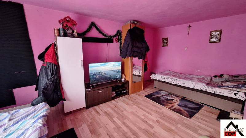 Rosa Zimmer in einem Einfamilienhaus mit Betten, Fernseher und Holzboden.