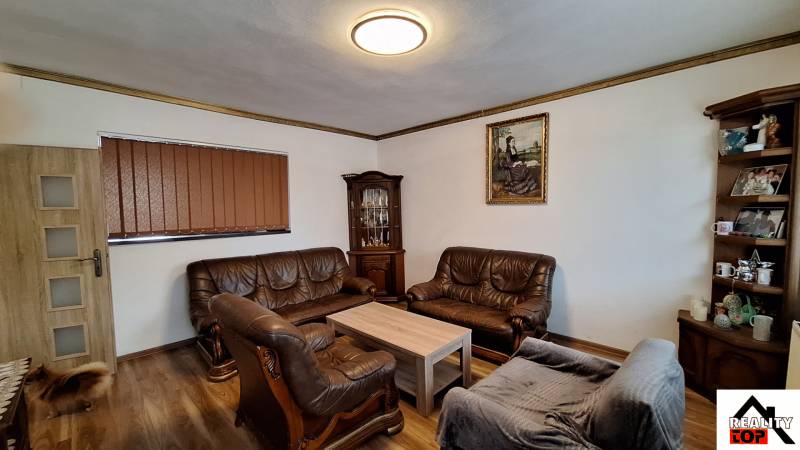 Wohnzimmer in einem Einfamilienhaus mit Ledersofas und einem Boden in Holzoptik.