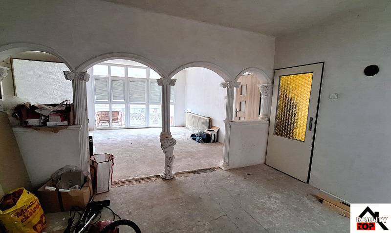 Das Innere eines Einfamilienhauses mit gewölbten Bögen und Glastüren. Reparaturen sind im Gange.