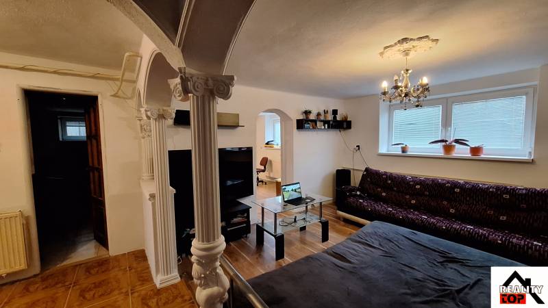 Wohnzimmer in einem Einfamilienhaus mit Sofa, Glastisch und Säulen.