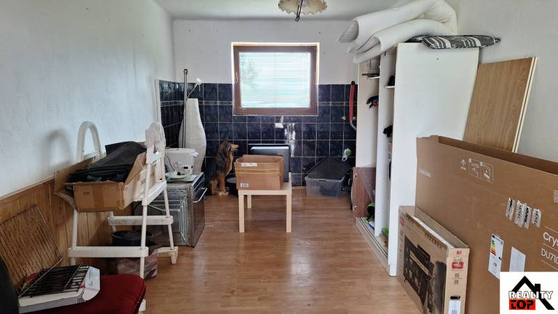 Ein Zimmer in einem Einfamilienhaus mit einem Boden in Holzoptik und vielen Kisten.